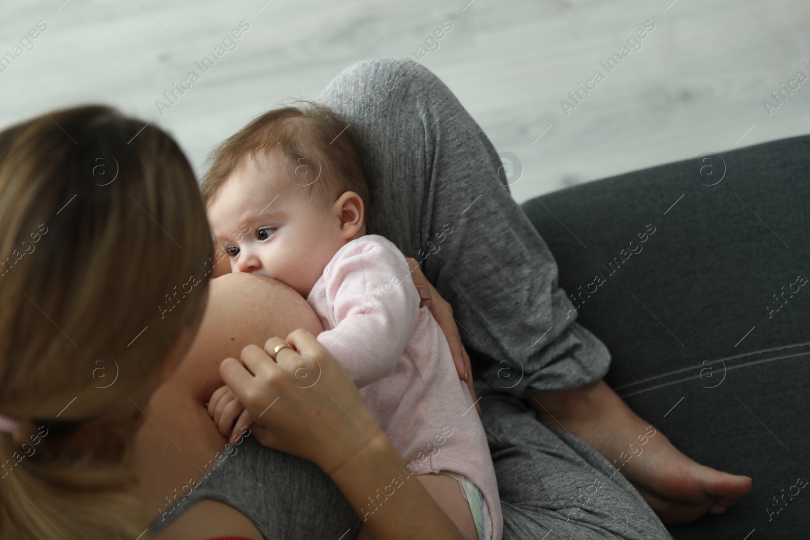 Photo of Young woman breastfeeding her baby at home, closeup