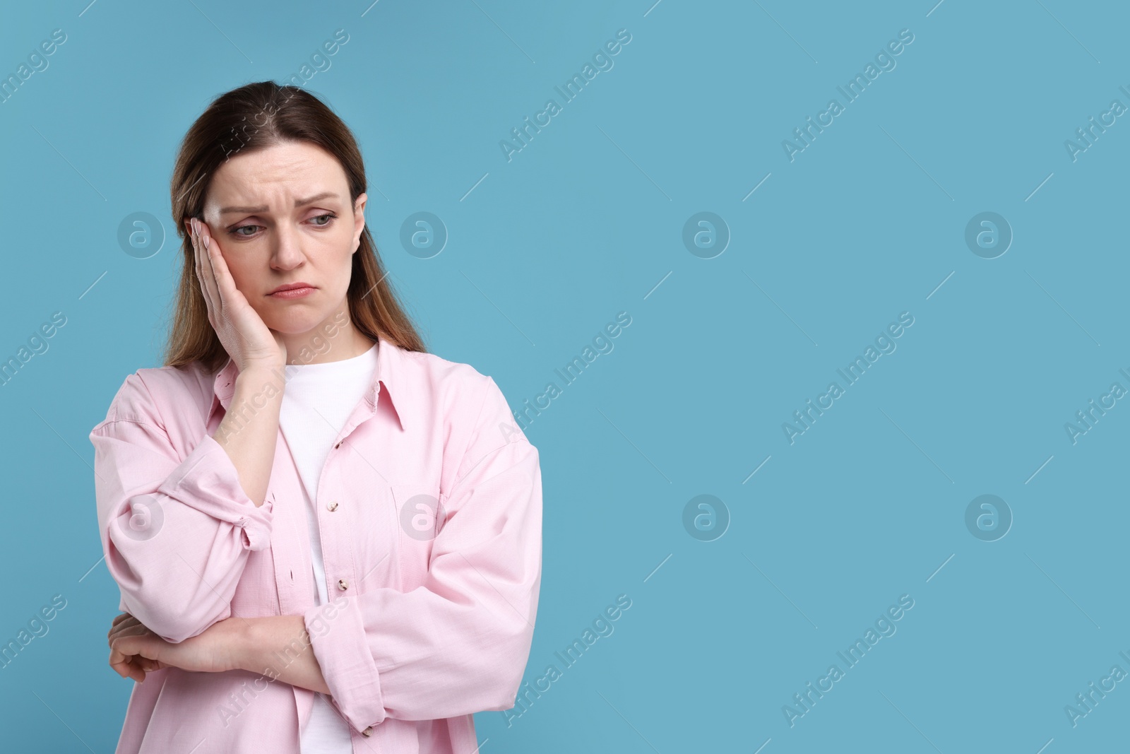 Photo of Portrait of sad woman on light blue background, space for text