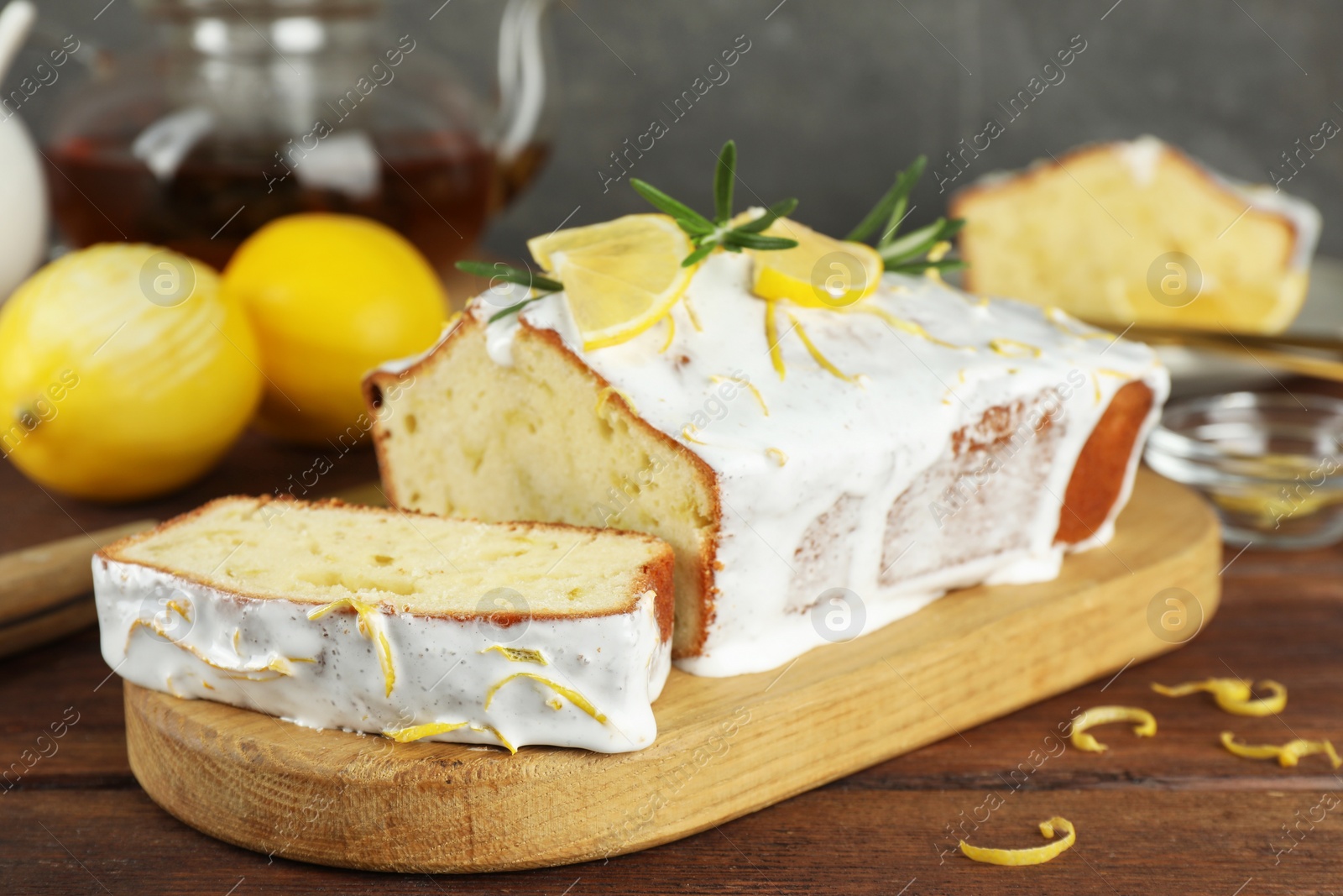 Photo of Tasty lemon cake with glaze and citrus fruits on wooden table, closeup