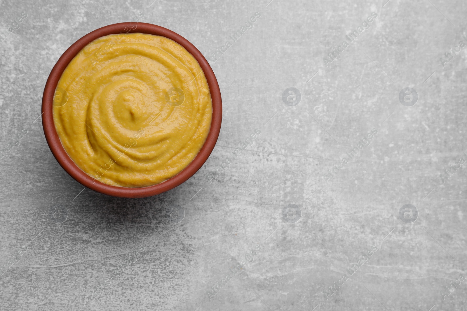 Photo of Bowl with delicious mustard on light grey table, top view. Space for text