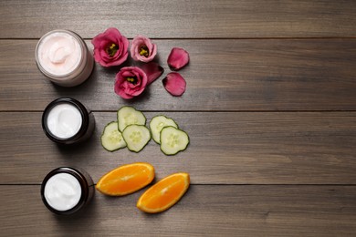 Photo of Flat lay composition with jars of face cream on wooden table, space for text