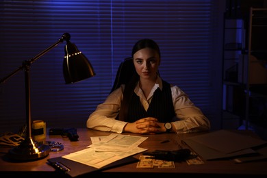 Photo of Professional detective working at table in office at night