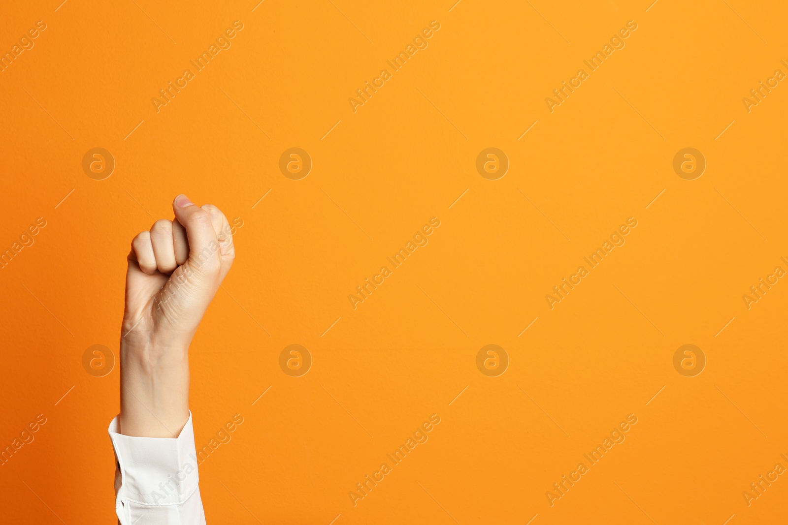Photo of Young woman showing clenched fist on color background. Space for text
