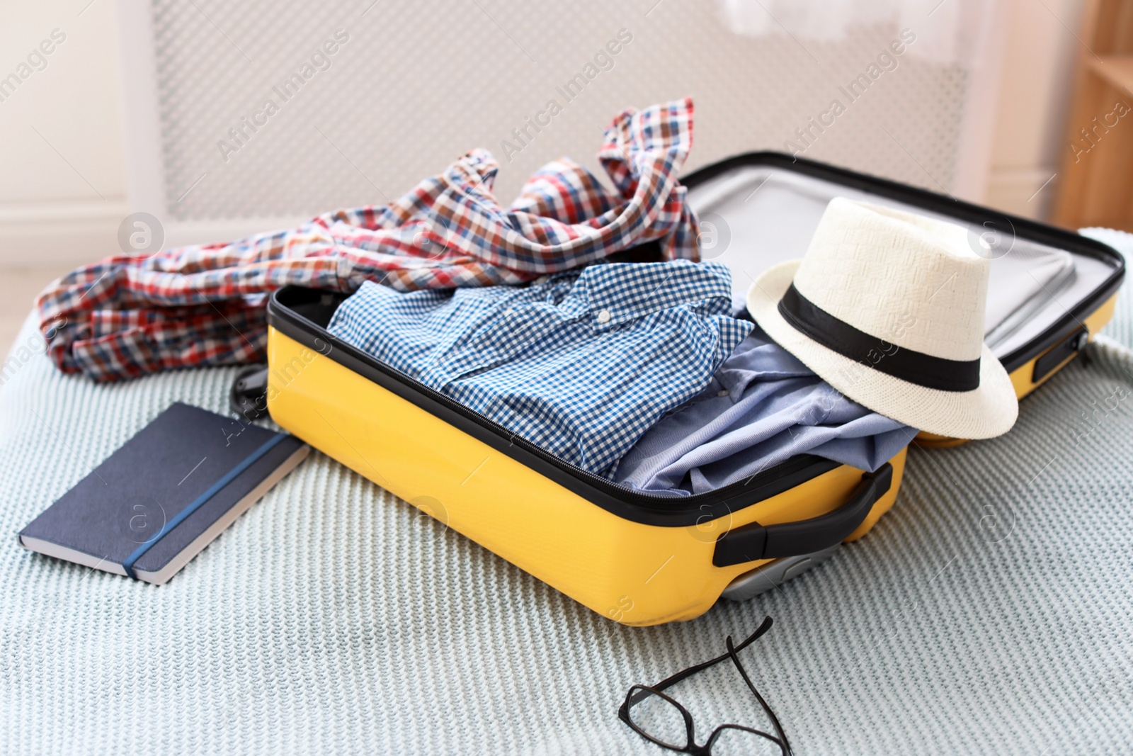 Photo of Open suitcase with packed clothes on bed