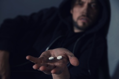 Photo of Young addicted man holding drugs, focus on hand