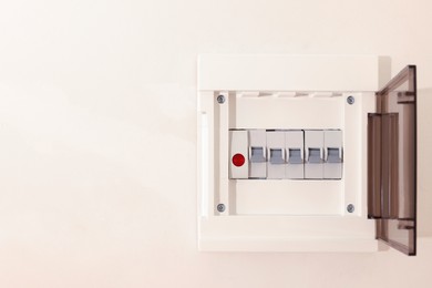 Photo of Open fuse box on beige wall. Space for text