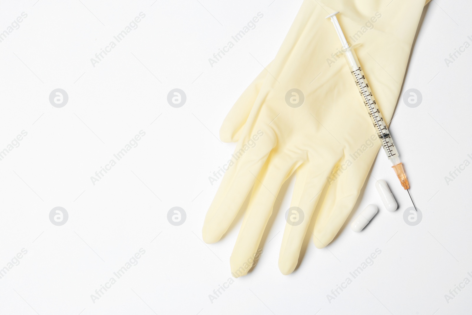Photo of Medical glove, pills and syringe on white background, top view