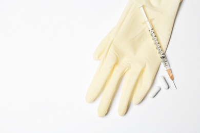 Medical glove, pills and syringe on white background, top view