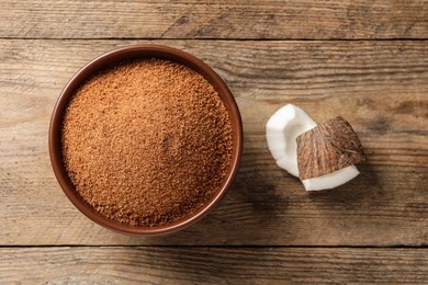 Photo of Natural coconut sugar in bowl on wooden table, flat lay