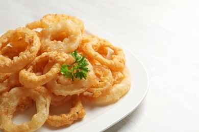 Homemade crunchy fried onion rings in plate on white background, closeup