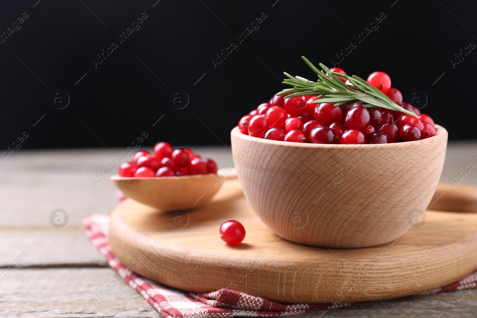 Photo of Fresh ripe cranberries and rosemary on wooden table