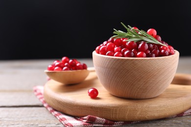 Photo of Fresh ripe cranberries and rosemary on wooden table