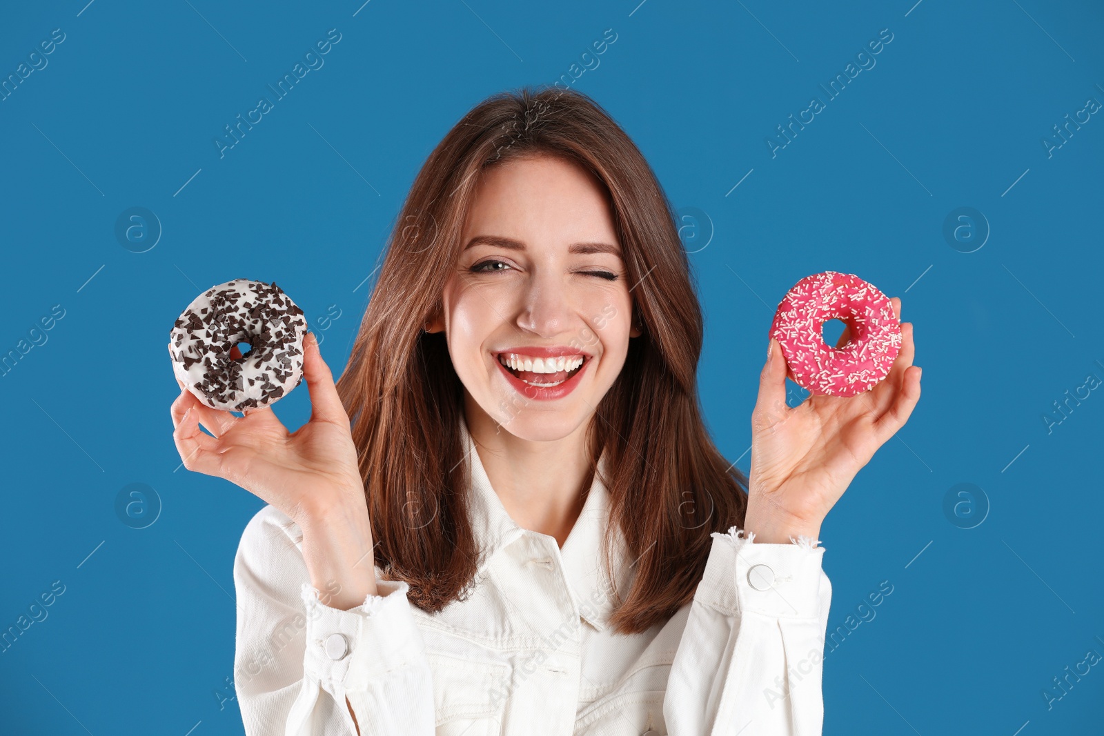 Photo of Beautiful young woman with donuts on blue background