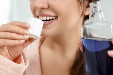 Photo of Young woman using mouthwash on blurred background, closeup