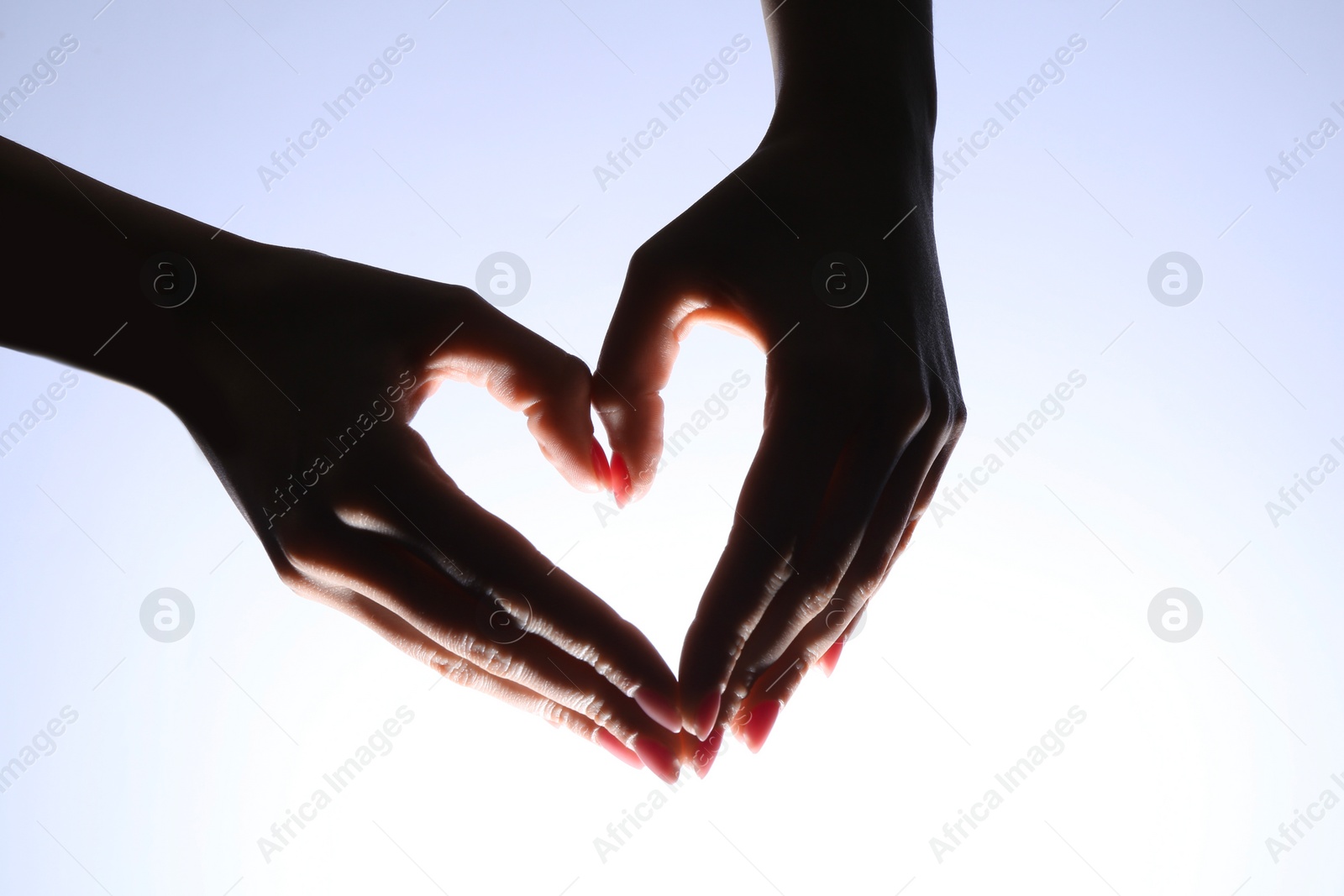 Photo of Woman making heart gesture on light background, closeup