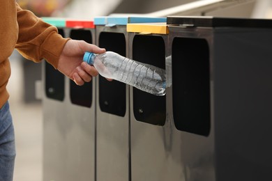 Photo of Man throwing plastic bottle into sorting bin outdoors, closeup