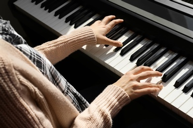 Photo of Young woman playing piano at home, closeup