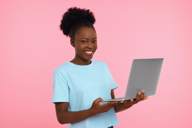 Photo of Happy young woman with laptop on pink background