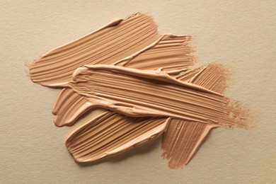 Photo of Samples of liquid skin foundations on beige background, top view