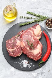 Photo of Fresh raw beef cut with different spices on light grey textured table, flat lay