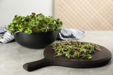 Photo of Board and bowl with fresh radish microgreens on light grey table