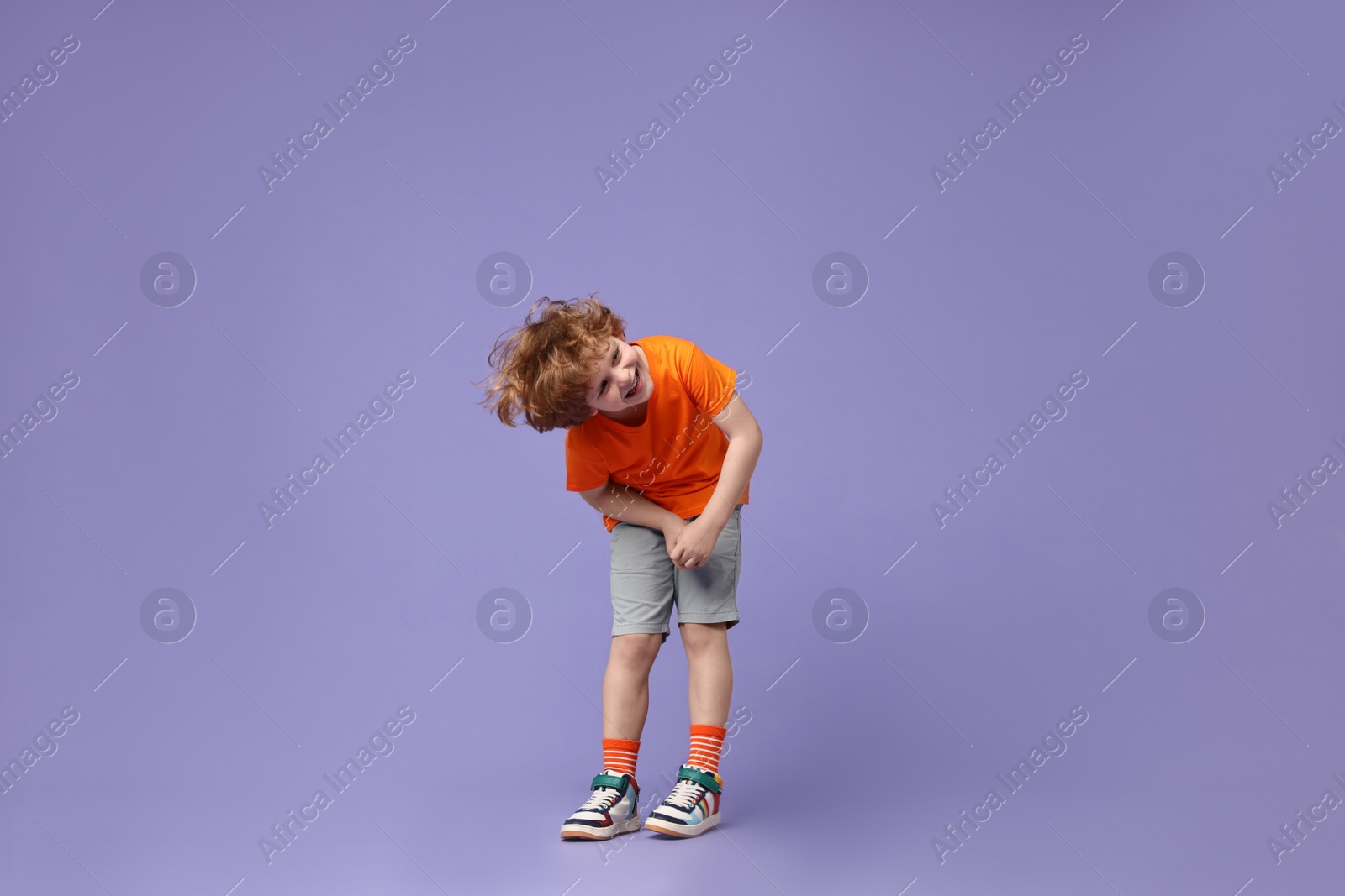 Photo of Happy little boy dancing on violet background. Space for text