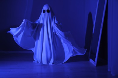 Creepy ghost. Woman covered with sheet in blue light