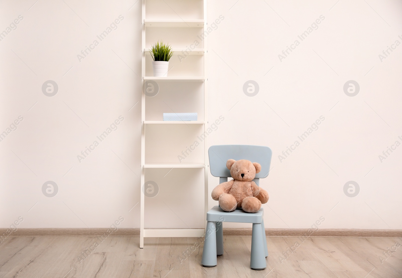 Photo of Teddy bear on chair and shelving unit near wall in child room