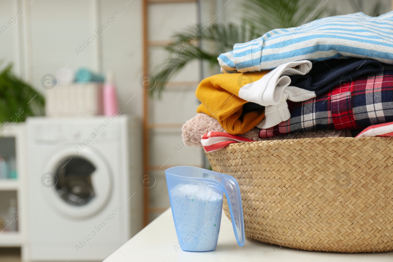Photo of Wicker basket with laundry and detergent on countertop in bathroom. Space for text