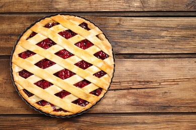 Photo of Delicious fresh cherry pie on wooden table, top view. Space for text