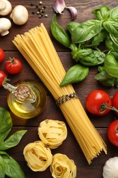 Different types of pasta, spices and products on wooden table, flat lay