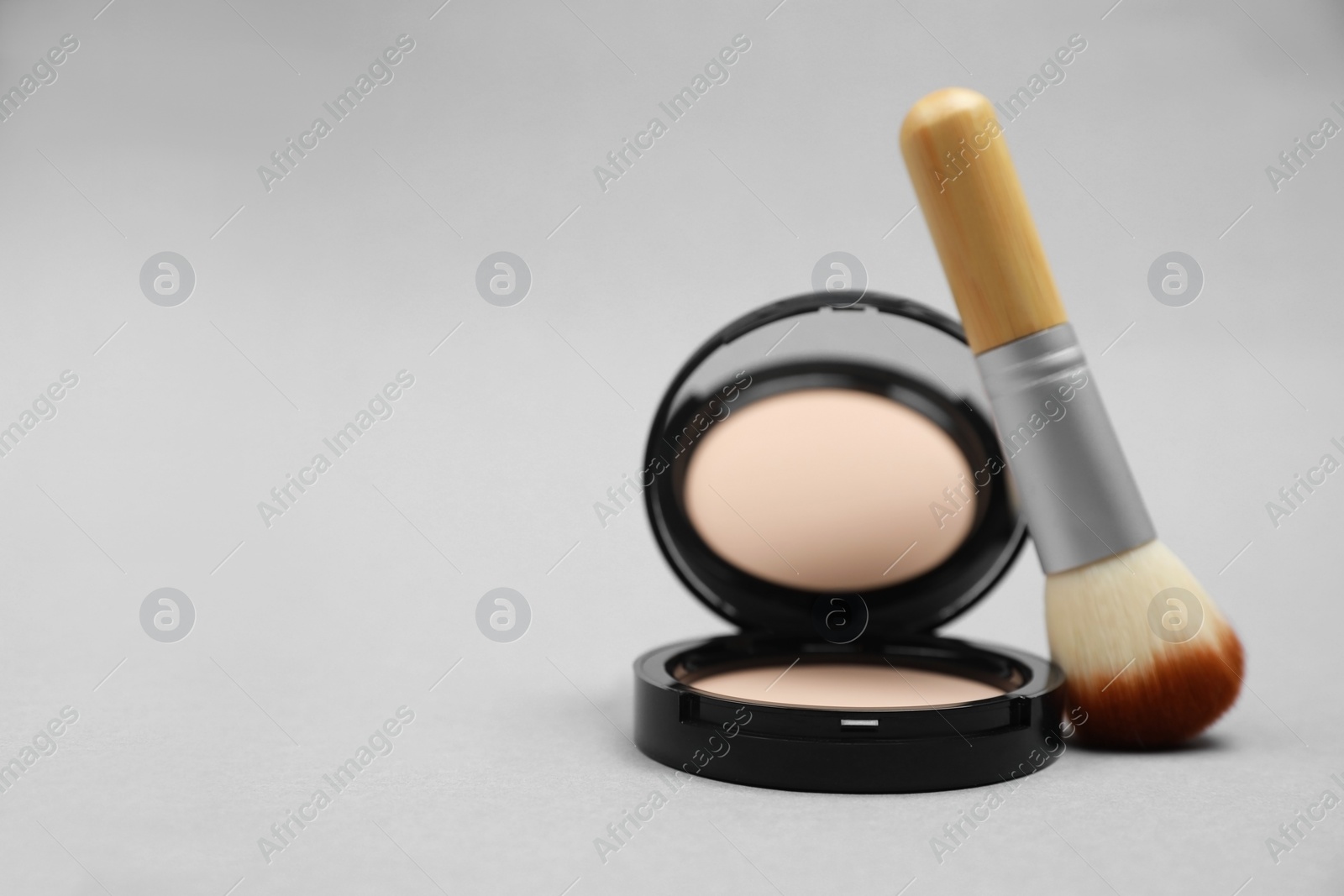 Photo of Face powder and brush on light grey background, closeup. Space for text