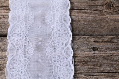 Photo of White lace on wooden table, above view. Space for text