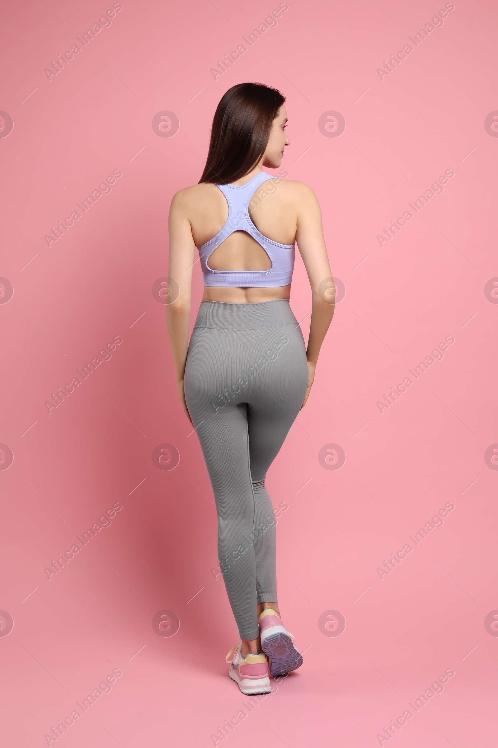 Photo of Woman with slim body on pink background, back view