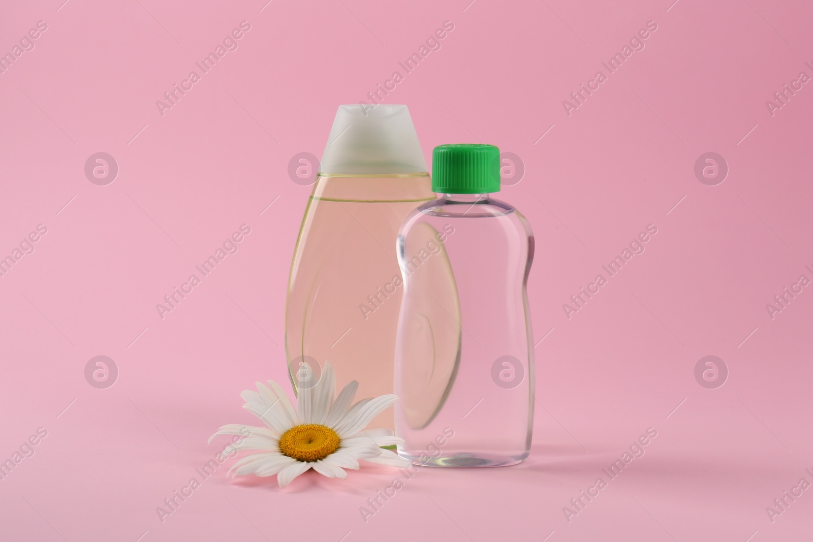 Photo of Bottles with baby oil and chamomile flower on pink background. Space for text