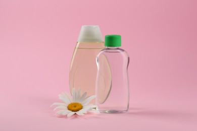 Photo of Bottles with baby oil and chamomile flower on pink background. Space for text