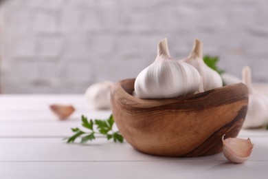 Fresh garlic on white wooden table, closeup. Space for text