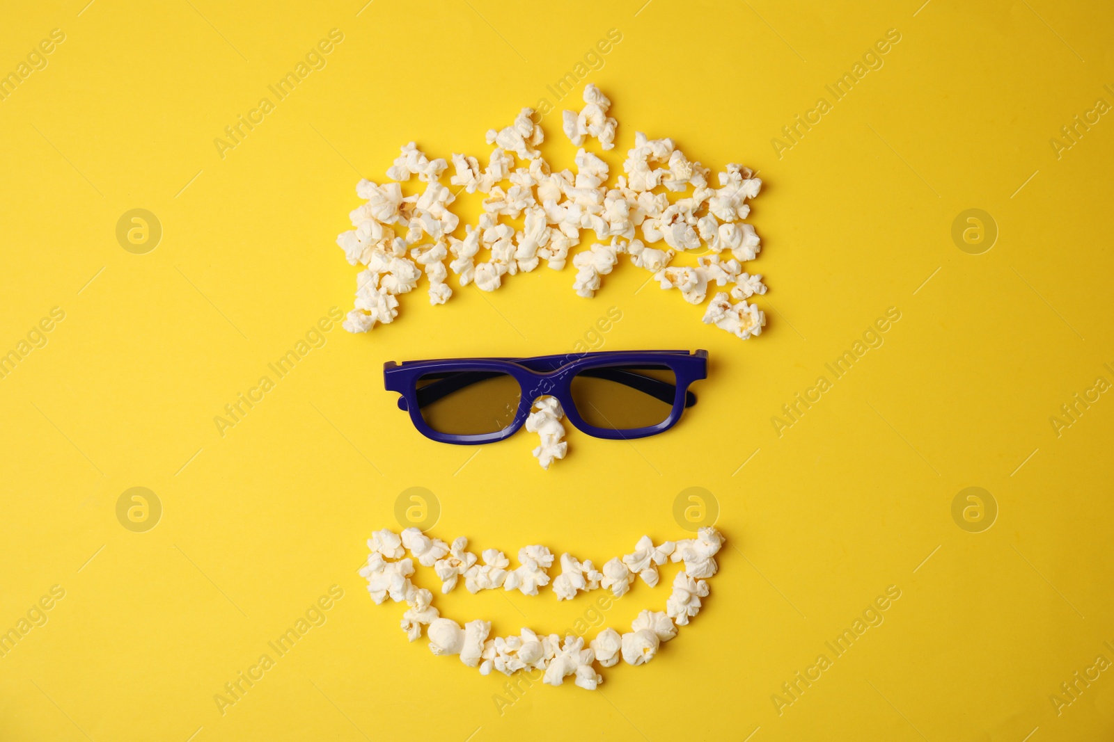 Photo of Face made with popcorn and glasses on color background, top view. Cinema snack