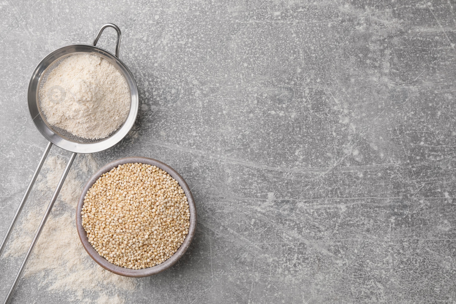 Photo of Quinoa flour in sieve and bowl with seeds on light grey table, flat lay. Space for text