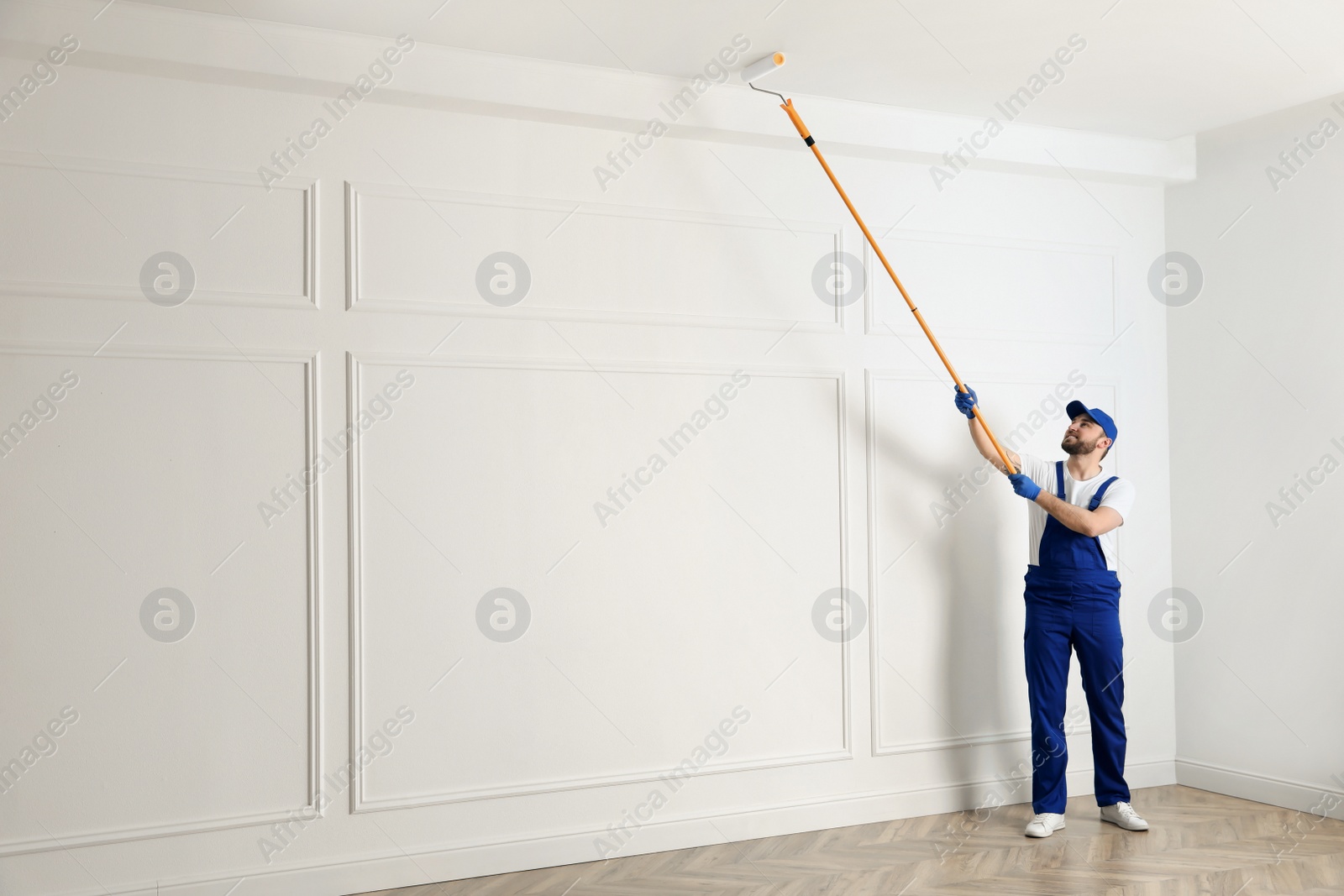 Photo of Handyman painting ceiling with white dye indoors, space for text