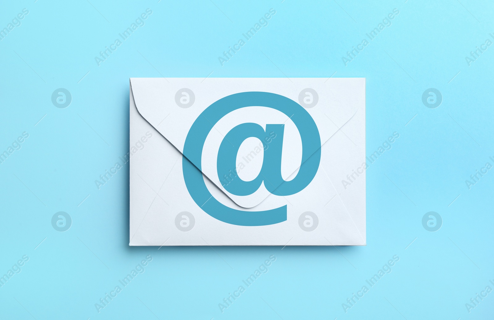 Image of White paper envelope with at sign on light blue background, top view. Email service