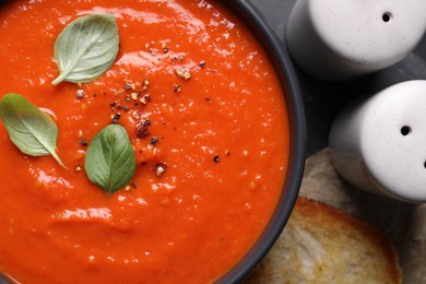 Photo of Delicious tomato cream soup served on black table, flat lay