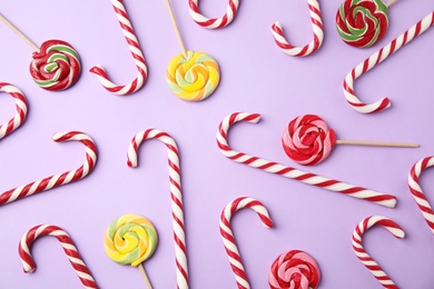 Photo of Flat lay composition with candy canes and lollipops on lilac background