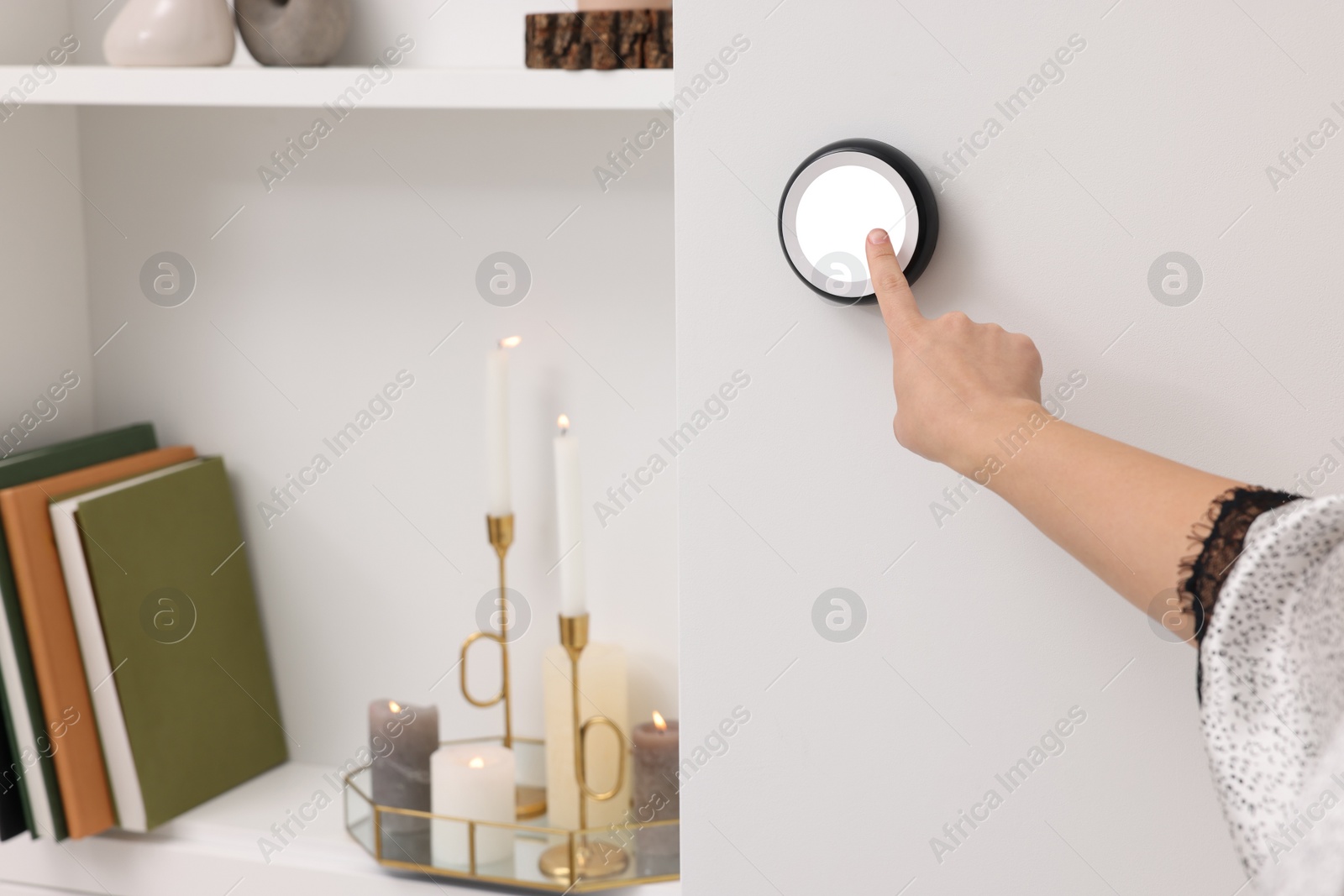 Photo of Woman adjusting thermostat on white wall indoors, closeup. Smart home system