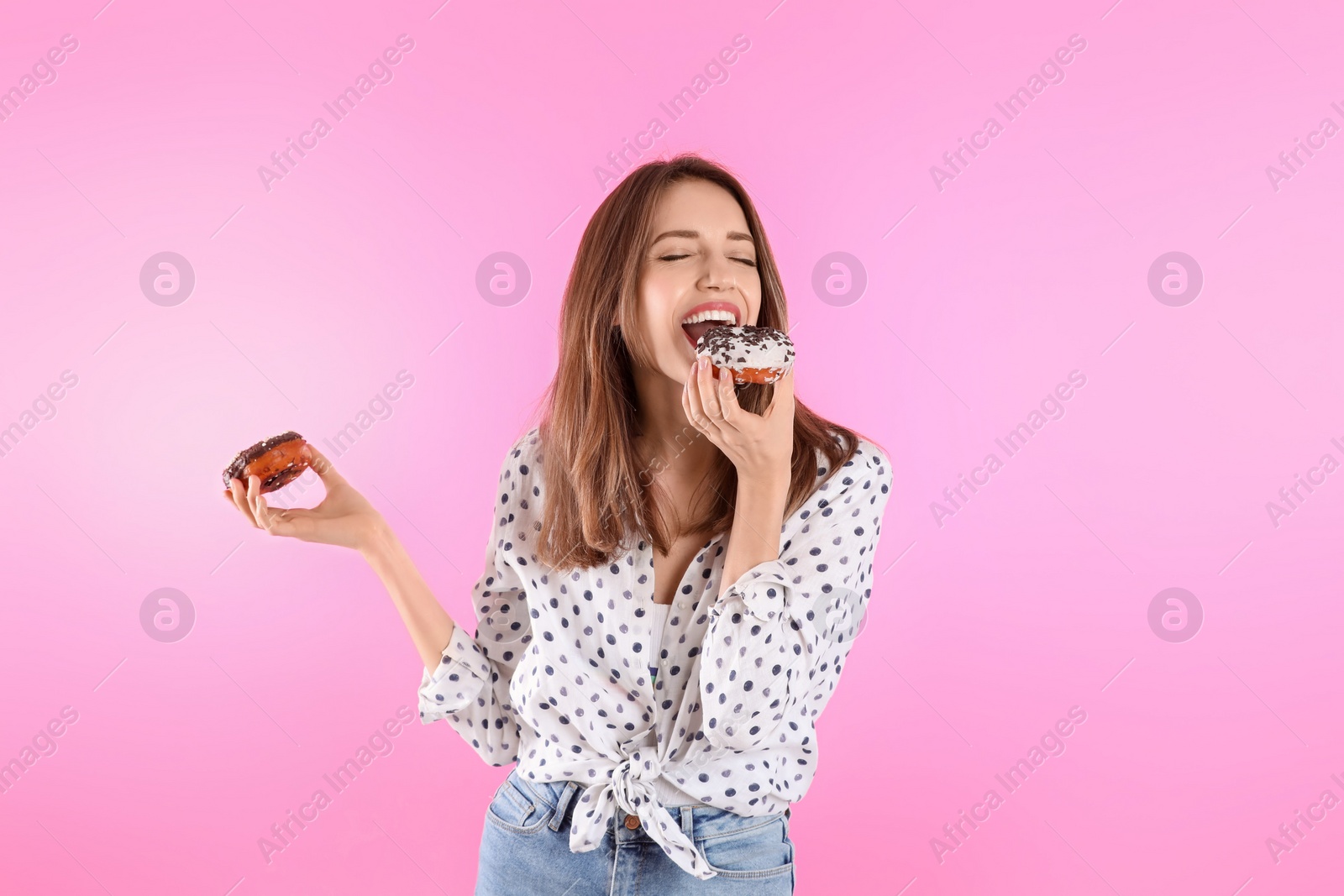 Photo of Beautiful young woman with donuts on light pink background