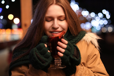 Photo of Happy woman with tasty mulled wine at winter fair