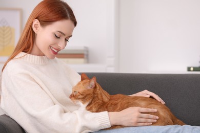 Photo of Happy woman with her cute cat on sofa at home