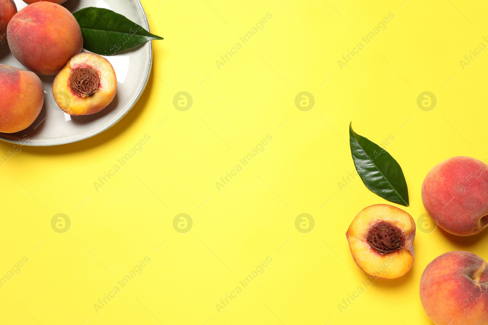 Photo of Delicious juicy peaches and green leaves on yellow background, flat lay. Space for text