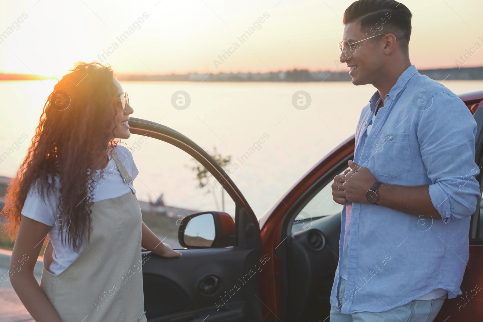 Photo of Happy couple near car outdoors at sunset. Summer trip