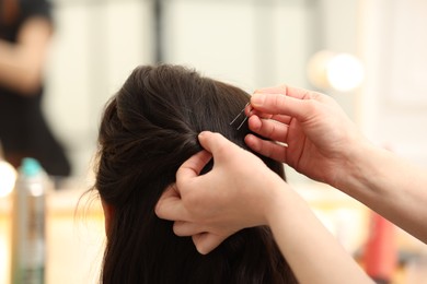 Hair styling. Professional hairdresser working with client indoors, closeup